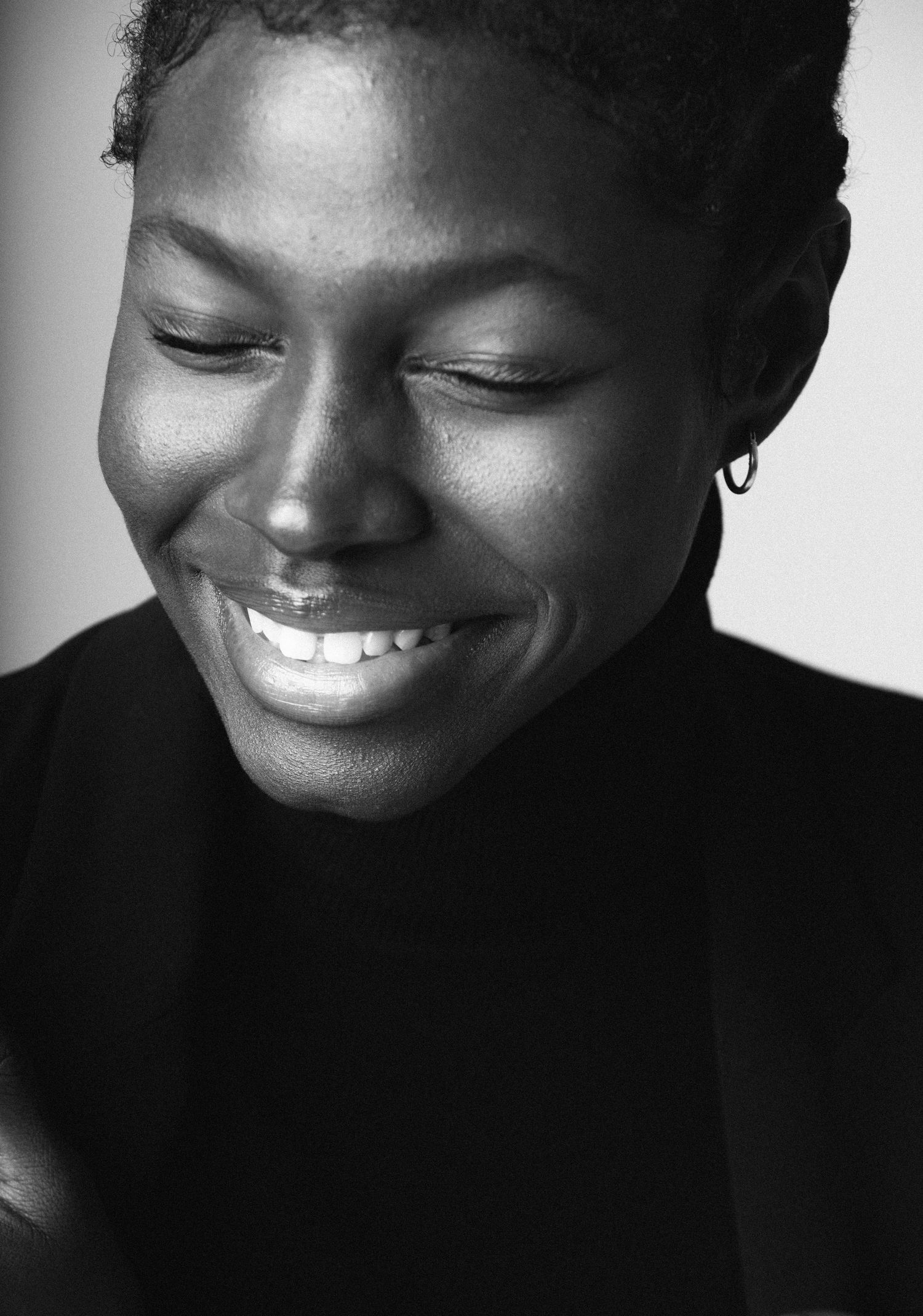 Black and white close-up portrait showing a joyful natural smile and closed eyes.