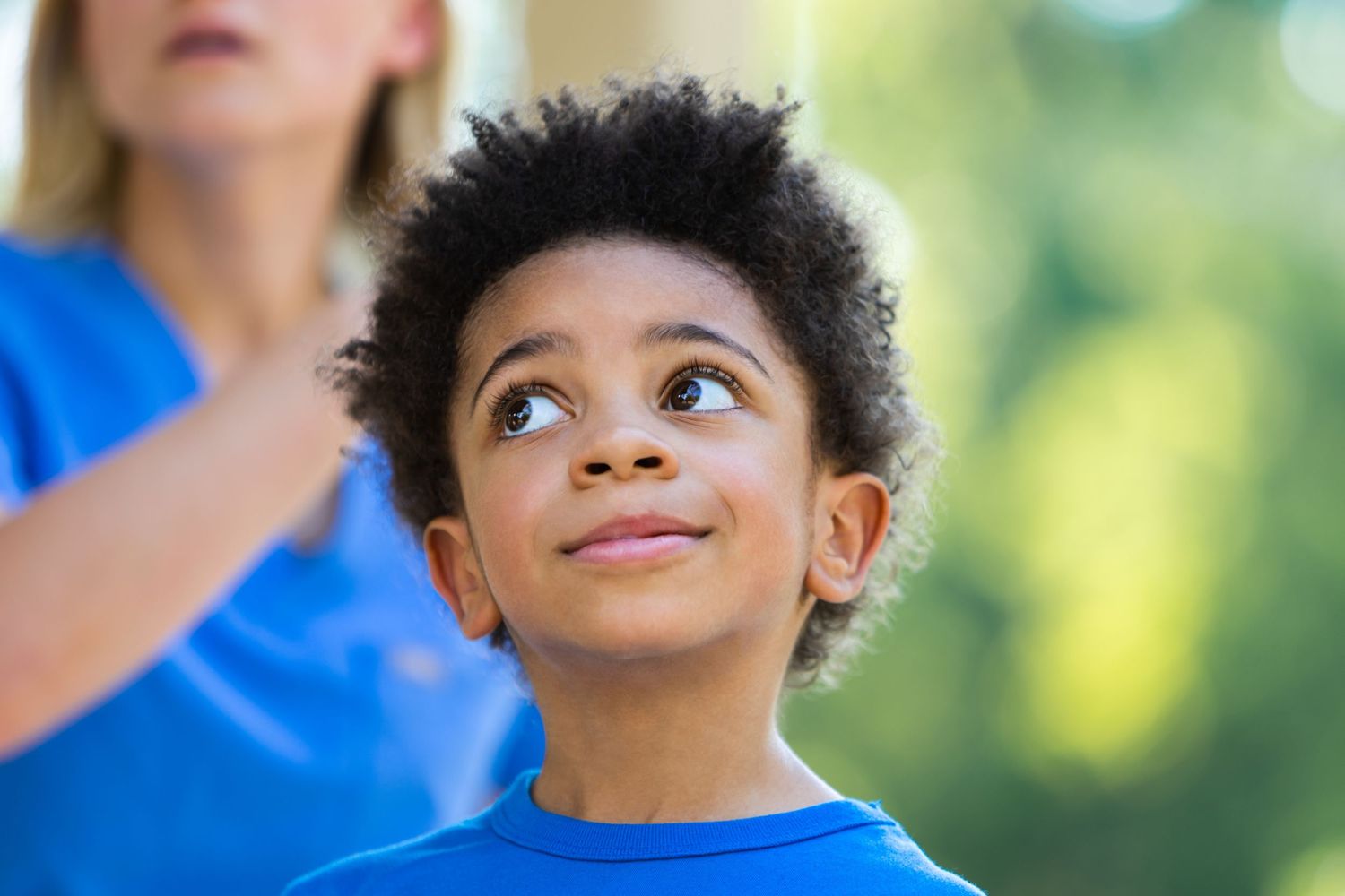 Young child in blue shirt looking up with wonder and excitement.