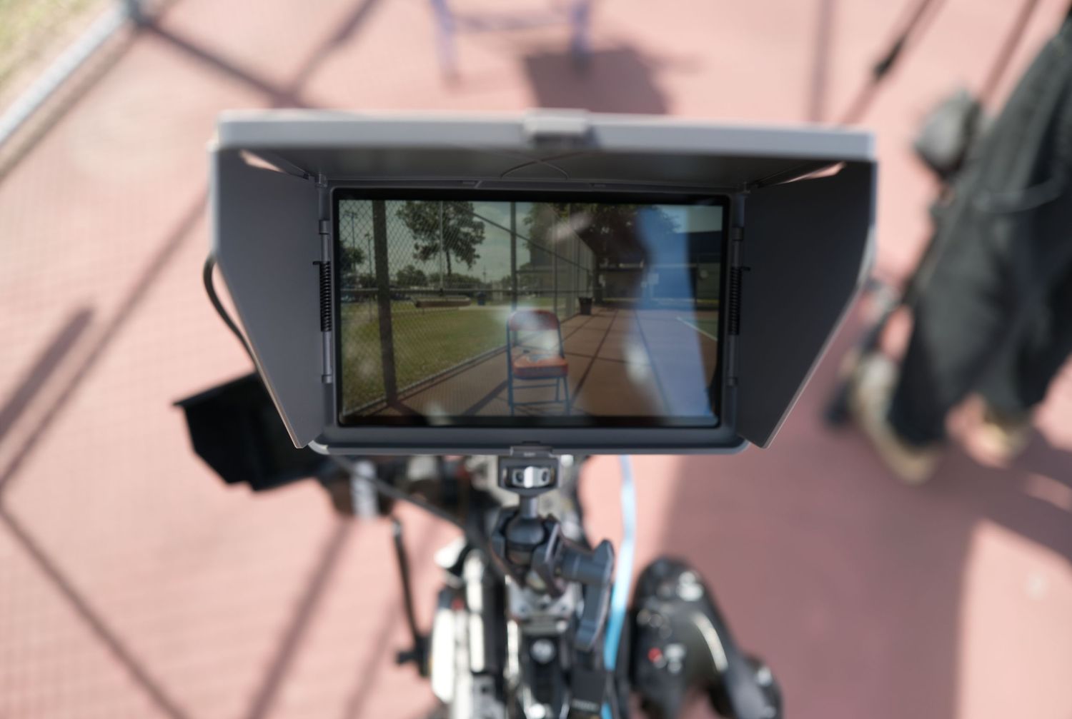 Professional video camera monitor displaying live outdoor footage on a tripod during a filming session.