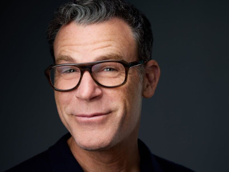 A series of seven headshots showing the same person with glasses making different facial expressions against a dark background.