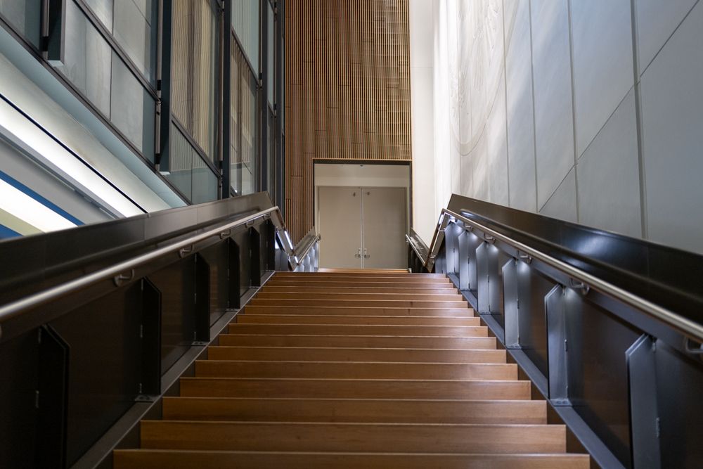 Modern wooden staircase with metal railings and LED lighting in commercial building.