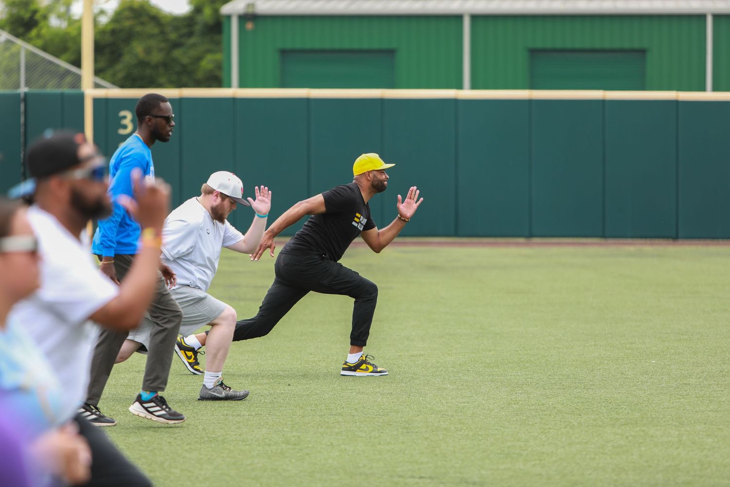 Athletes running sprints during training on outdoor athletic field.