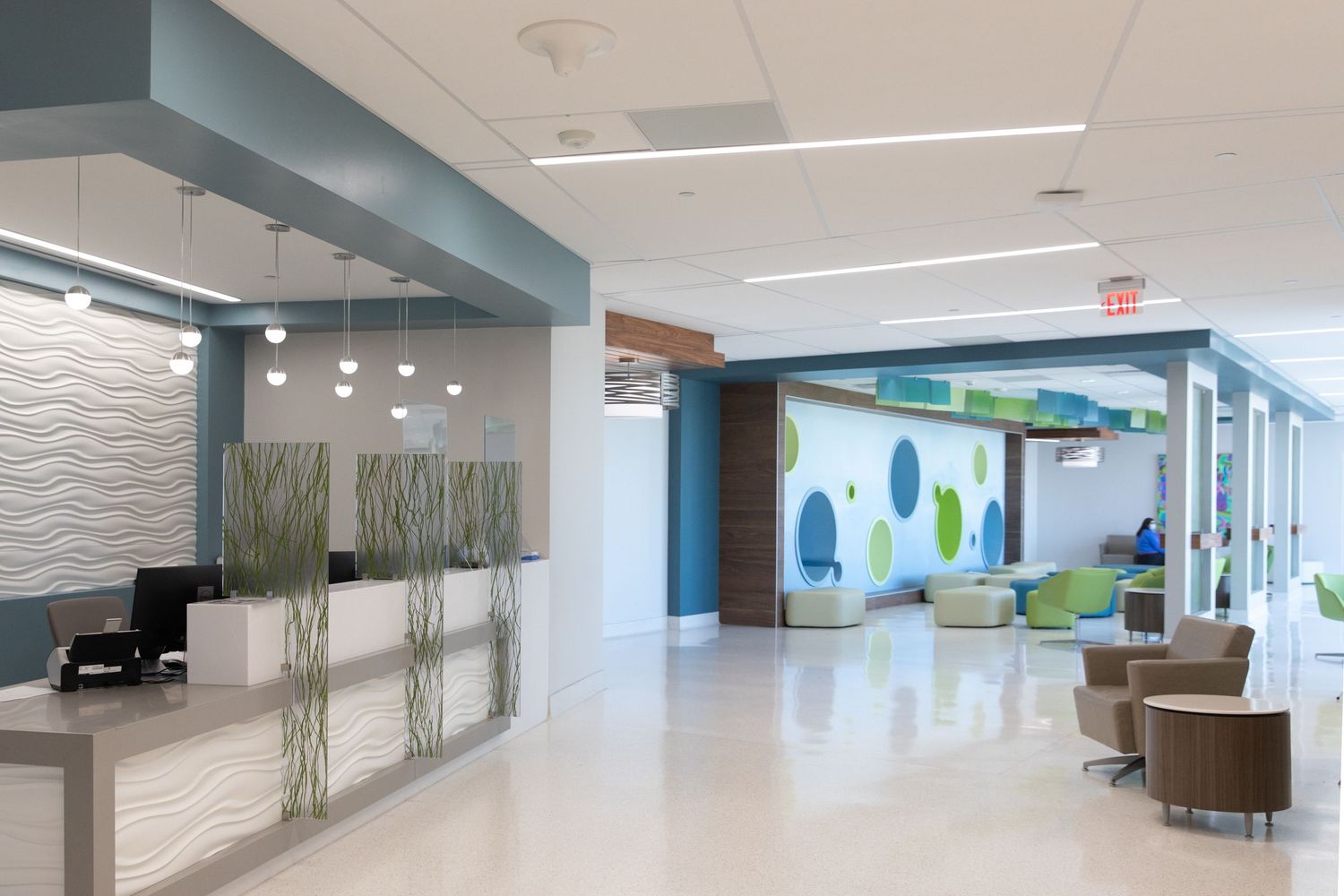 Modern medical office lobby with sleek reception desk and artistic wall designs.