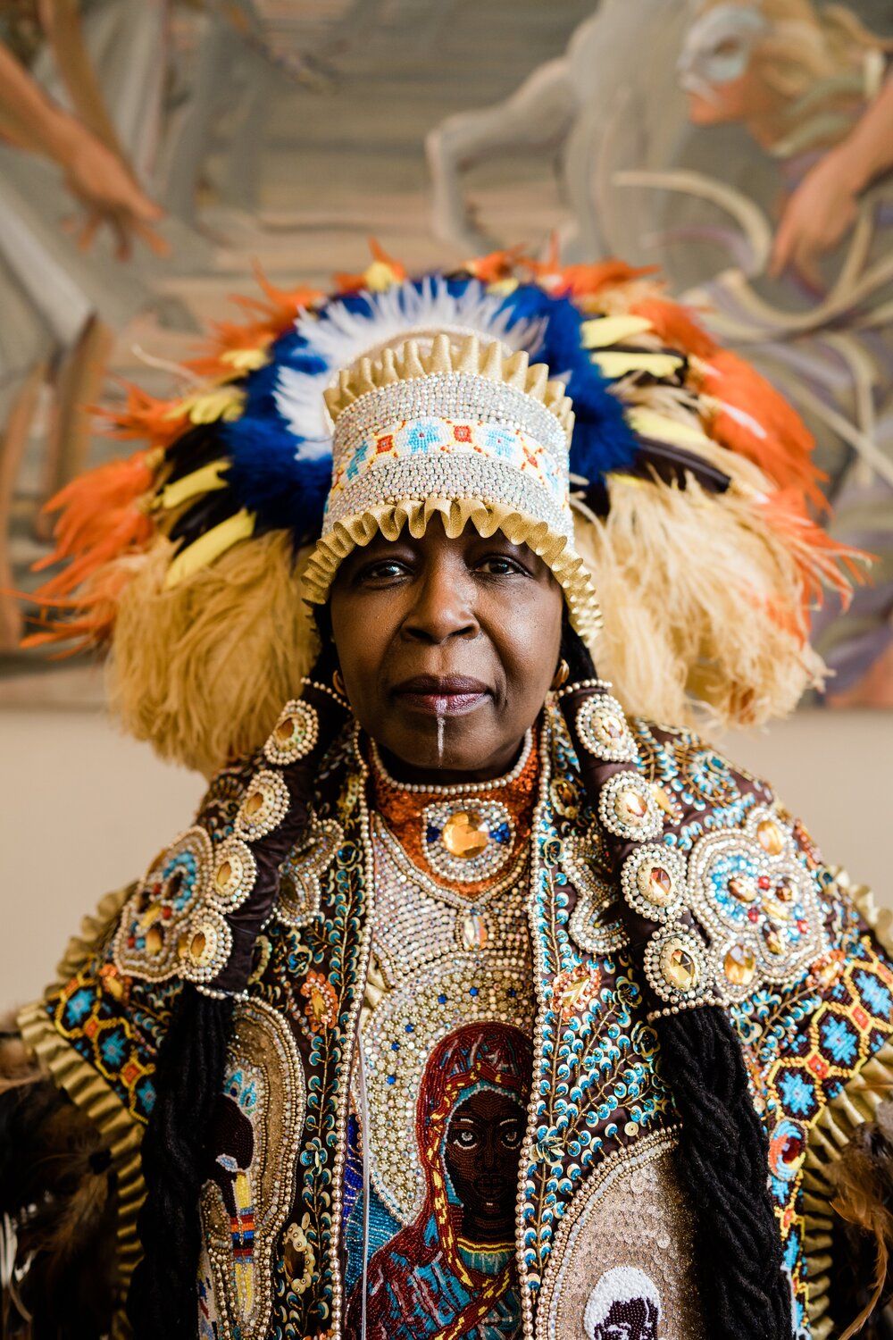 Ornate carnival costume featuring elaborate beadwork, feathers and decorative elements in blue, gold and orange colors.