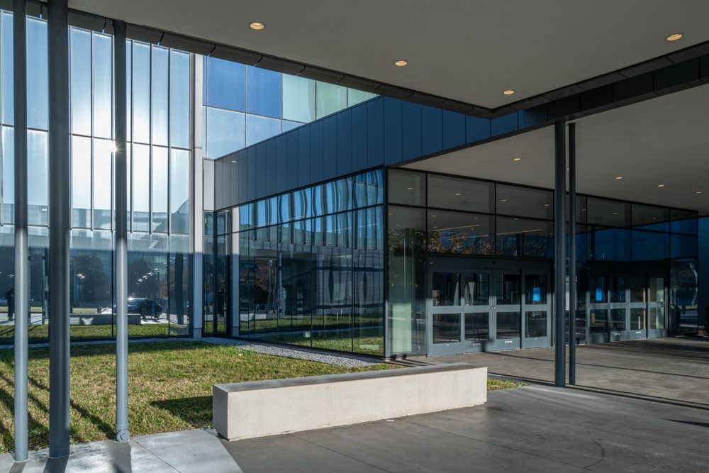 Glass and steel entrance to modern office building with landscaping.