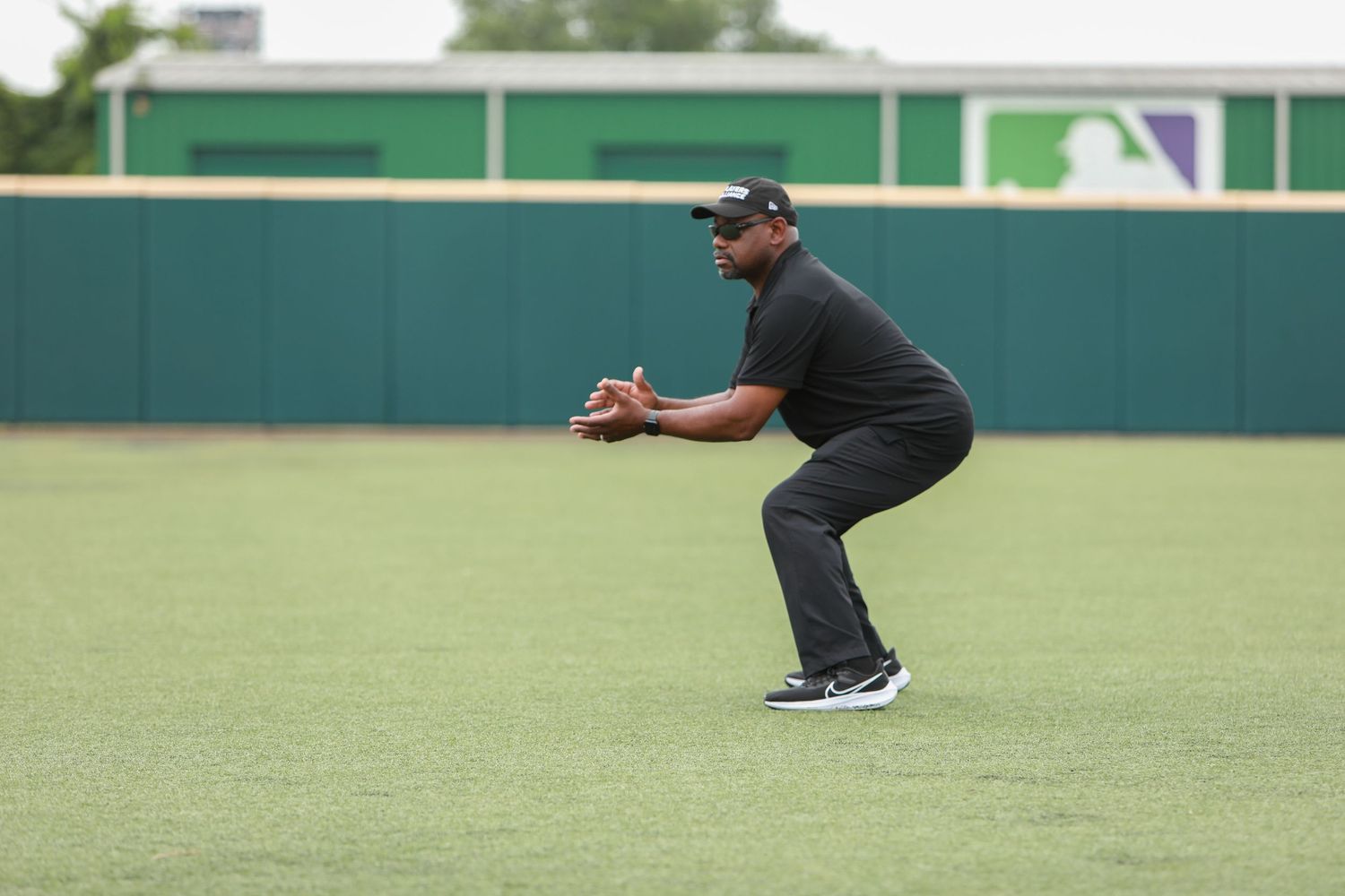 Person in baseball fielding stance on green turf field.