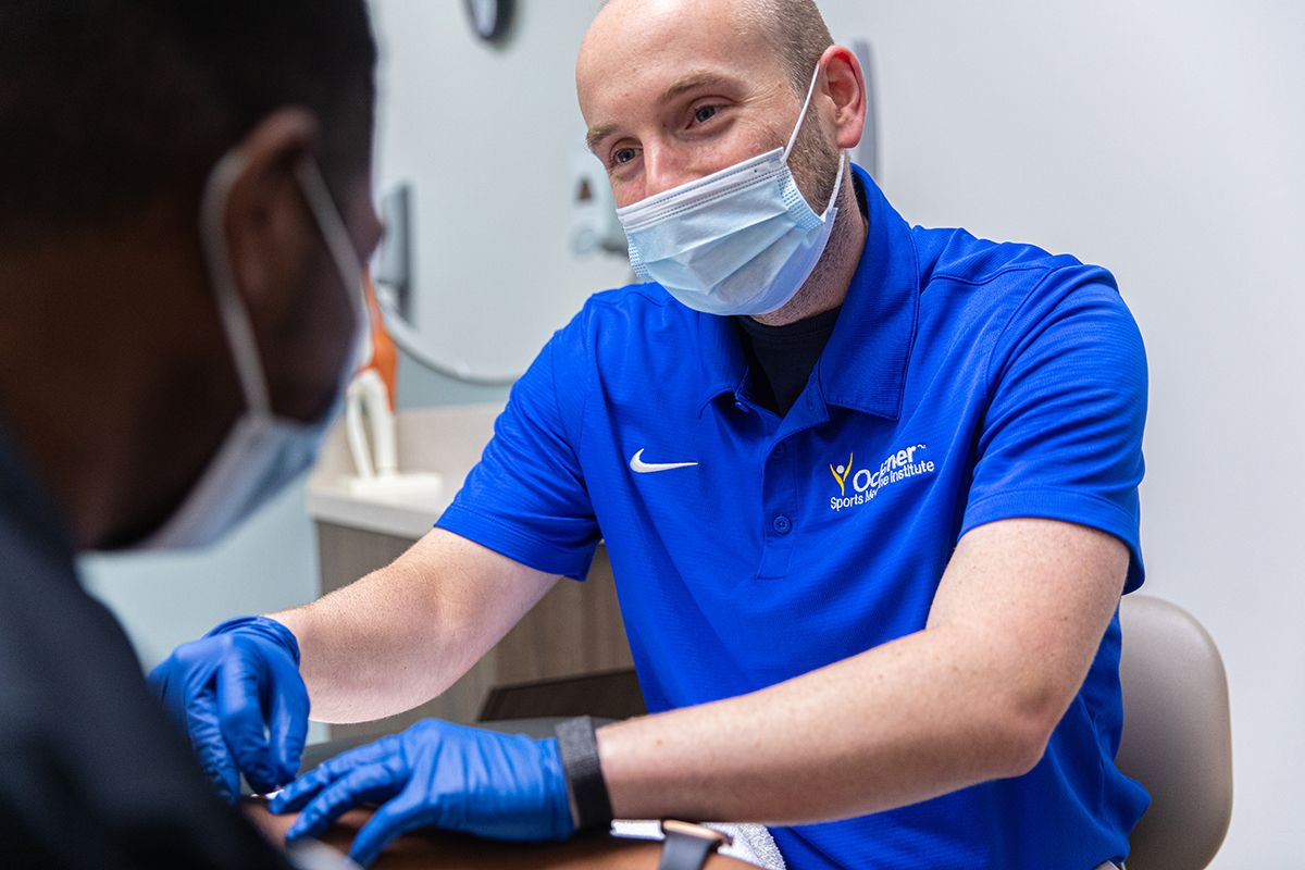 Healthcare provider in protective equipment conducting medical procedure.