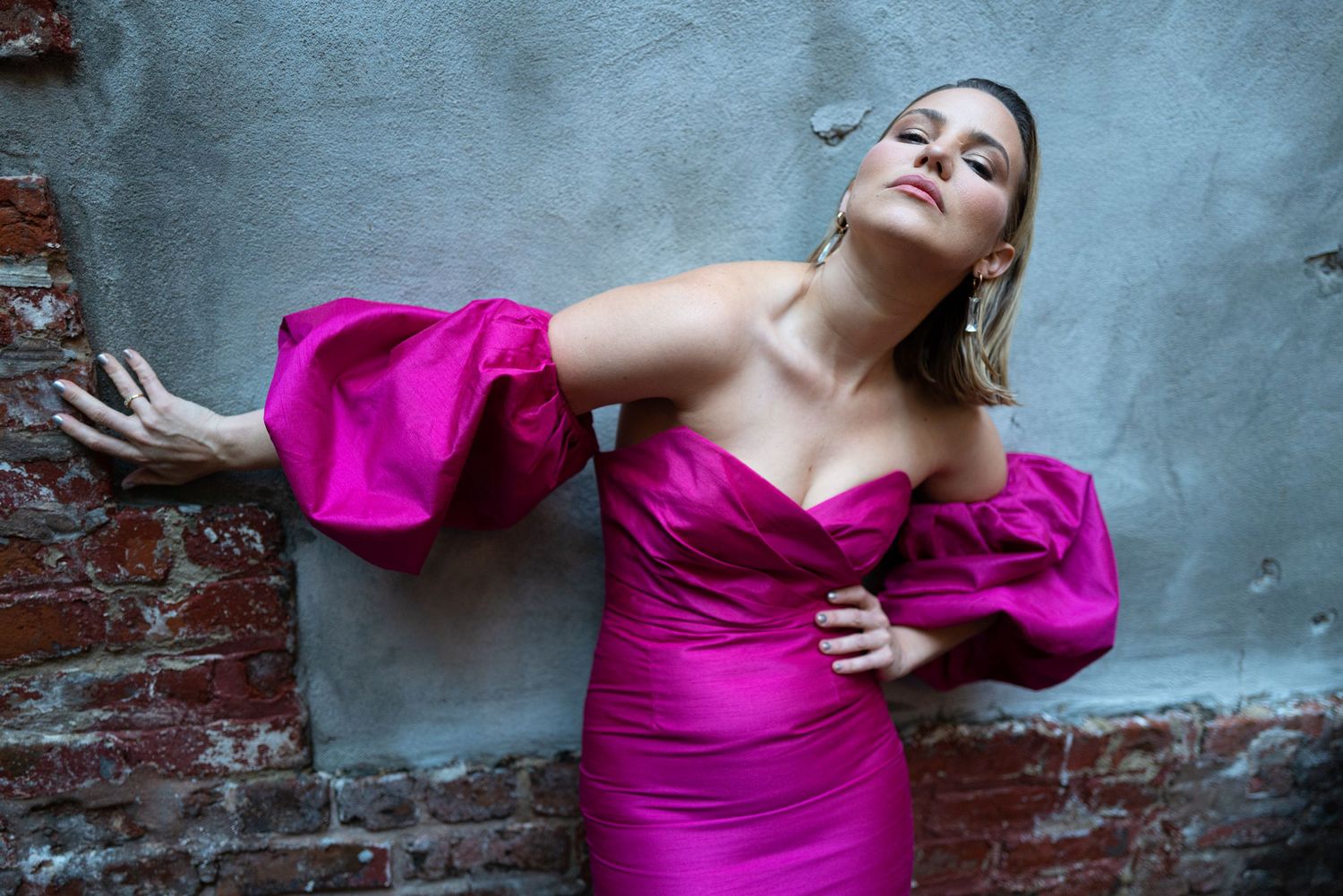 A person in a vibrant magenta dress poses dramatically against a textured gray wall in a series of artistic shots.