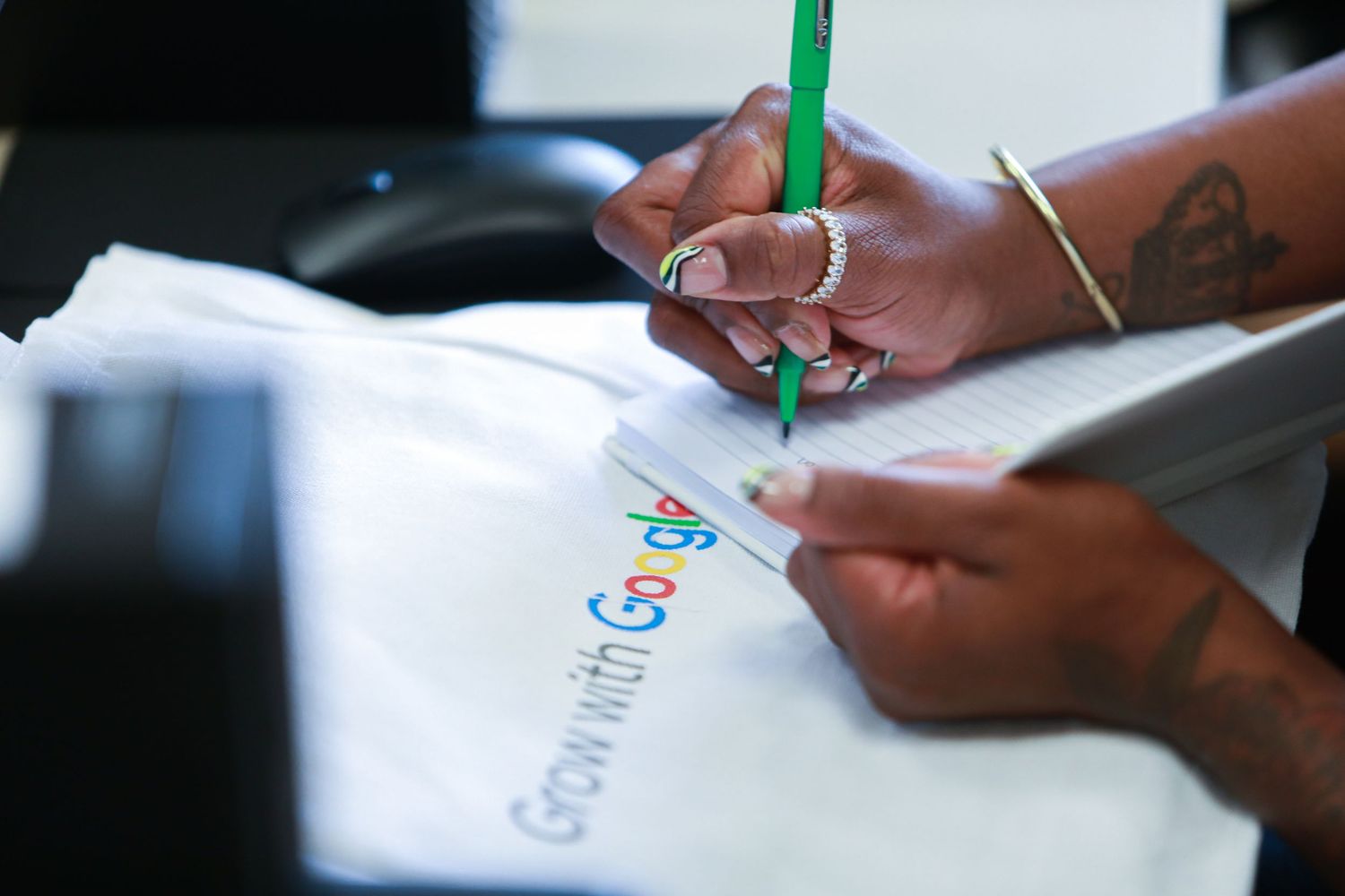 Hands write on a Google-branded document with a green pen.