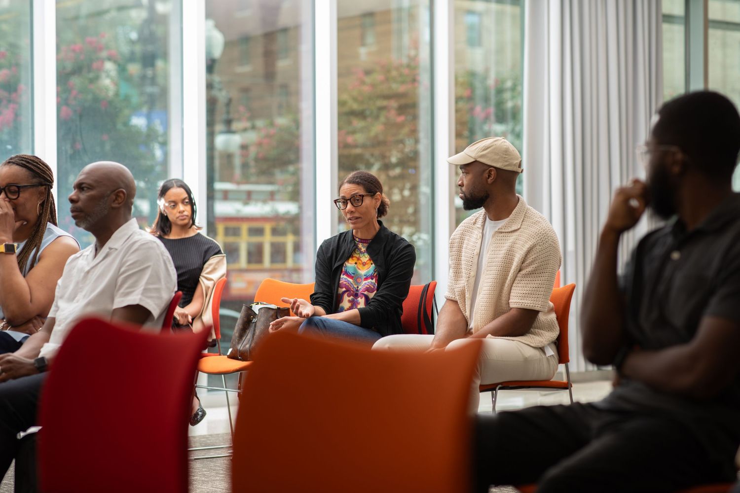 Diverse group of people gathered around tables in a community meeting or social gathering space.