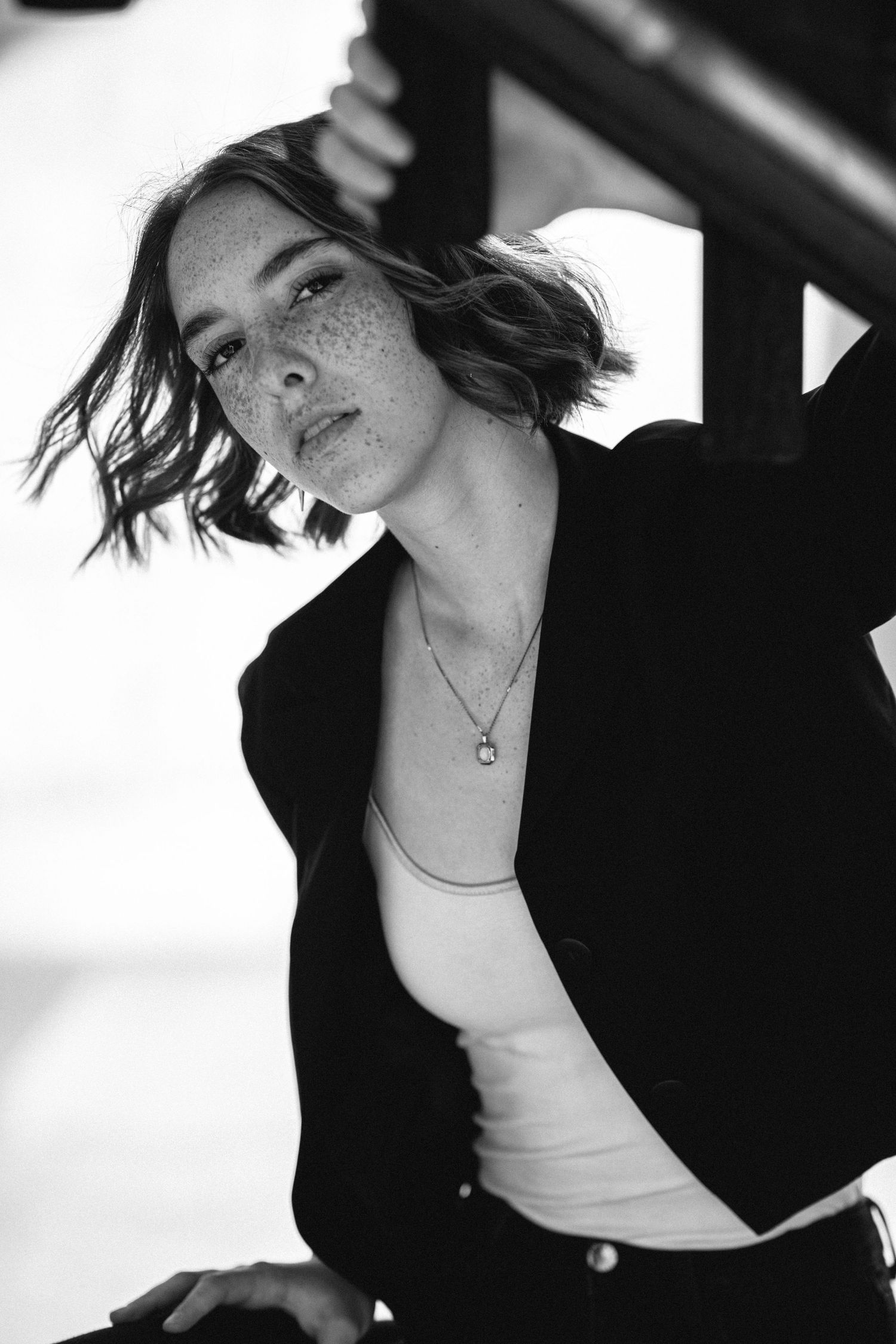 Black and white portrait of a person with freckles wearing a blazer and tank top.