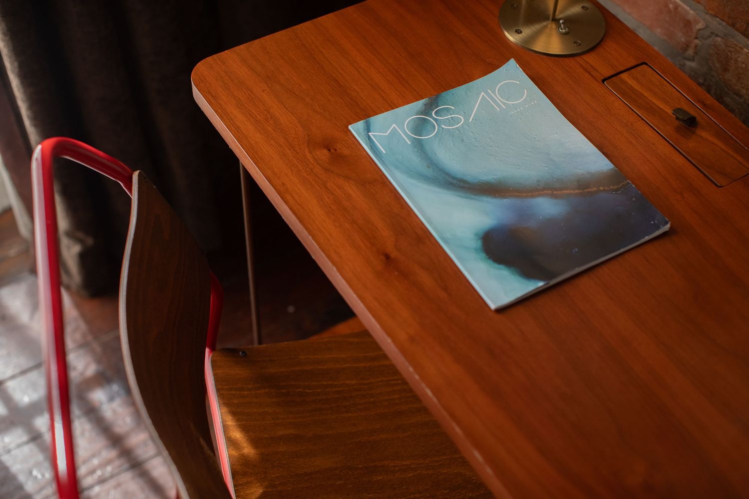 Wooden desk with magazine and lamp showing minimalist hotel room detail.