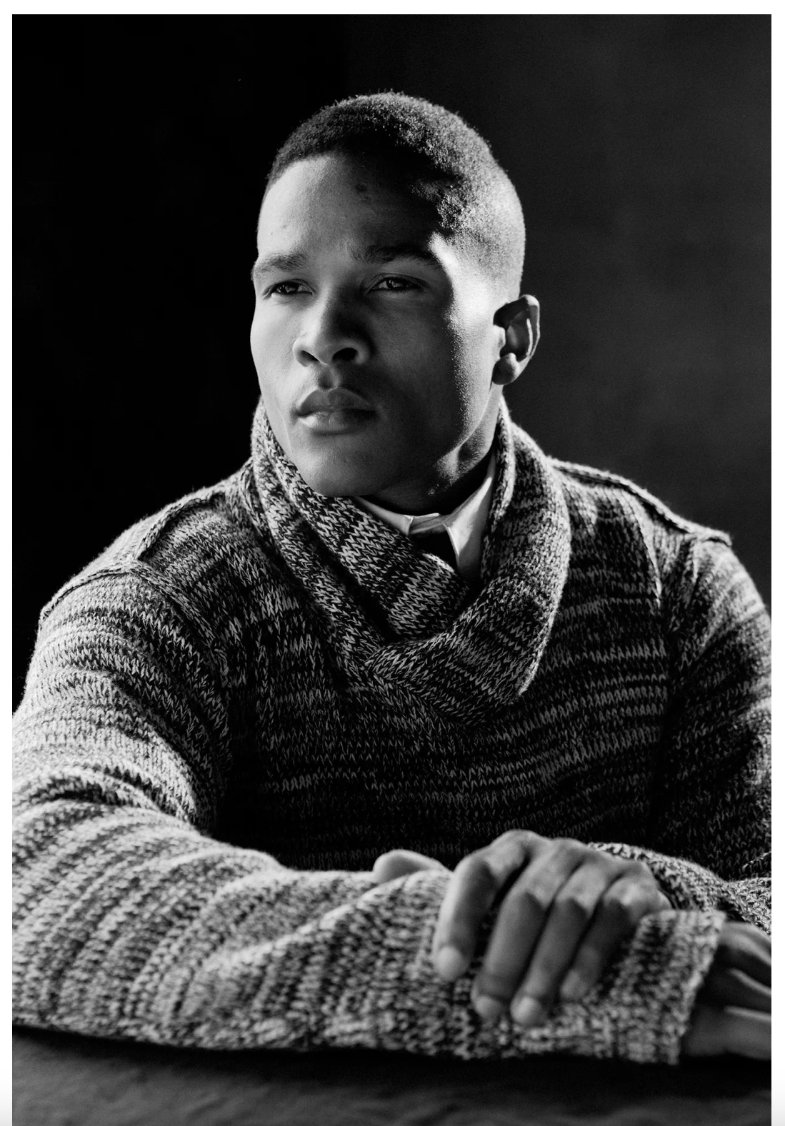 Dramatic black and white portrait of a person wearing a chunky knit sweater.