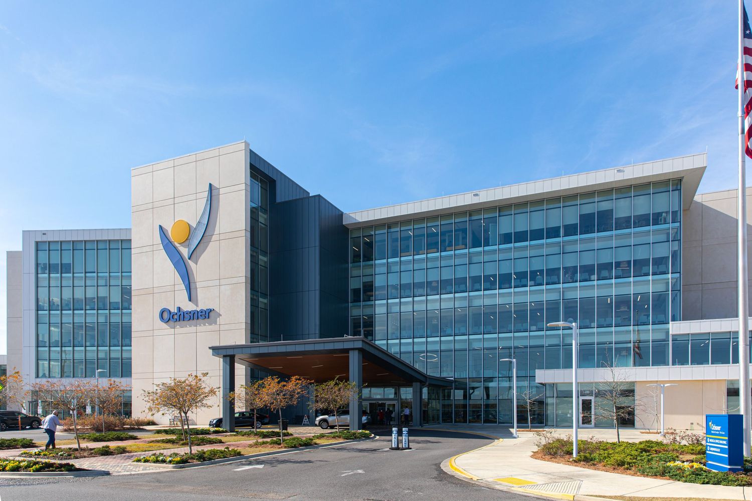 Modern glass office building exterior with blue sky and corporate logo.