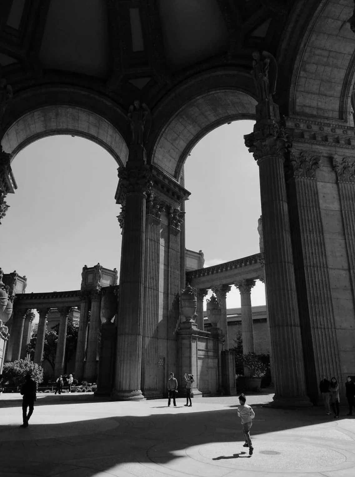 A sequence of black and white photographs showing silhouettes of people walking under grand architectural arches.