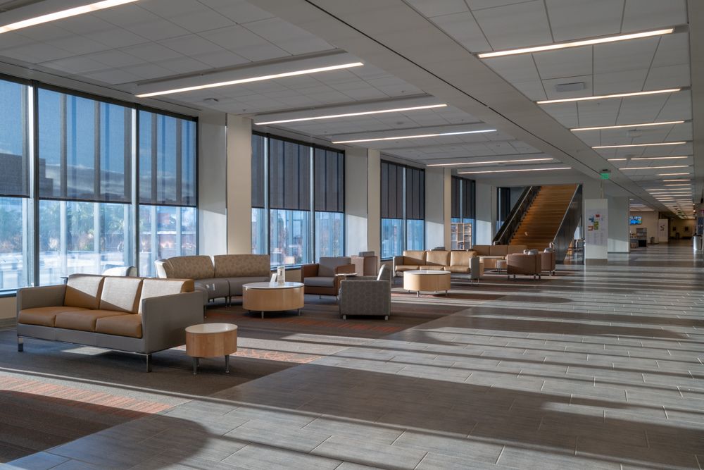 Contemporary office lounge area with tan seating and large windows.