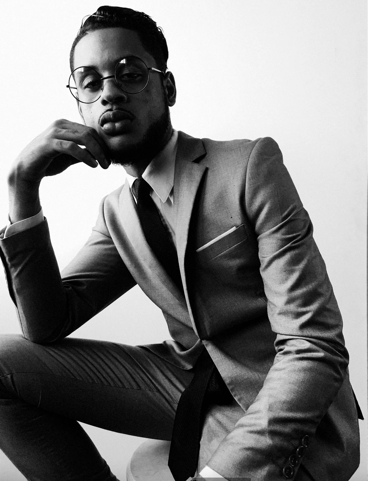 Stylish monochrome portrait of a person in a well-fitted suit posing thoughtfully.