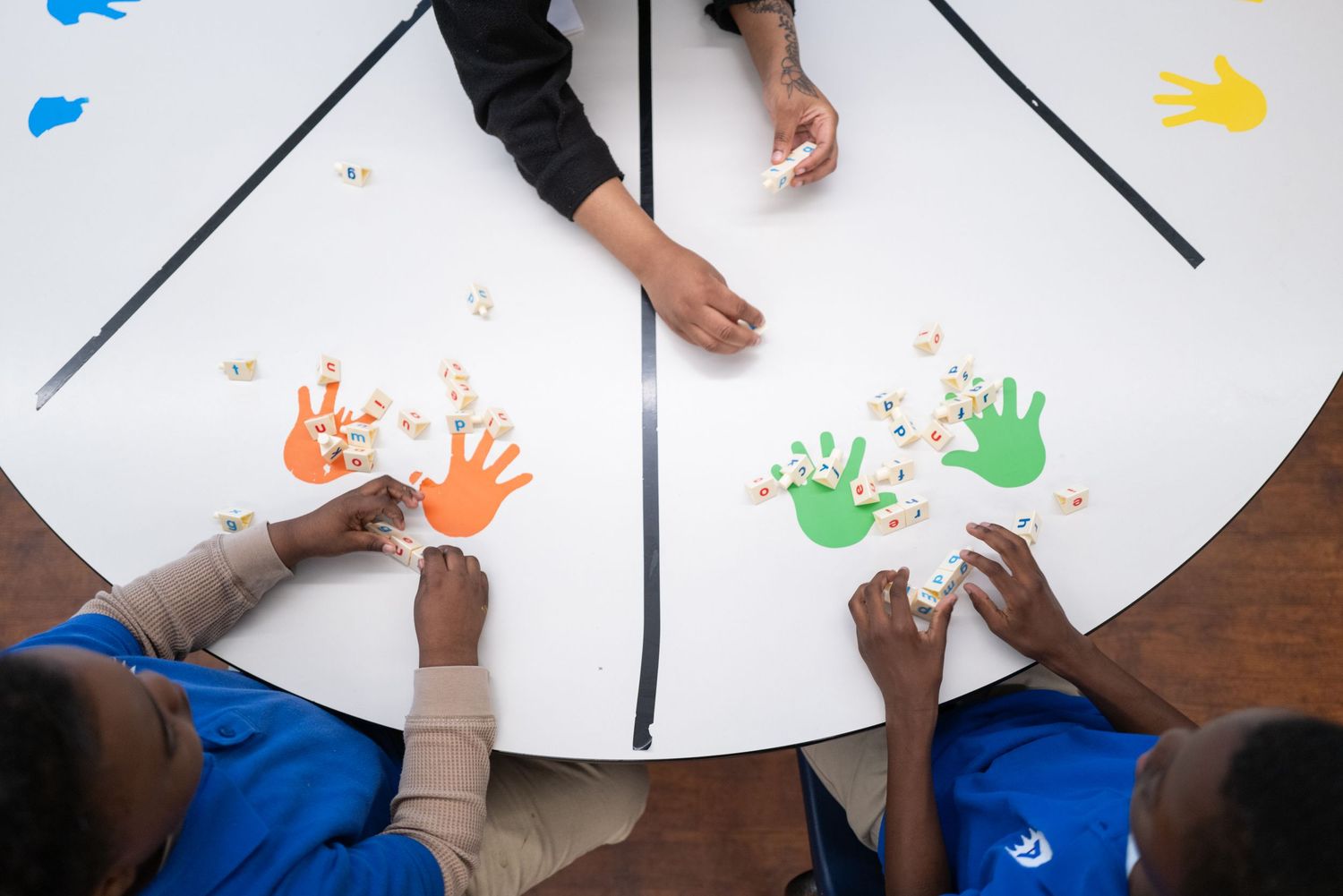 Students creating colorful handprint art on white paper during a creative activity.
