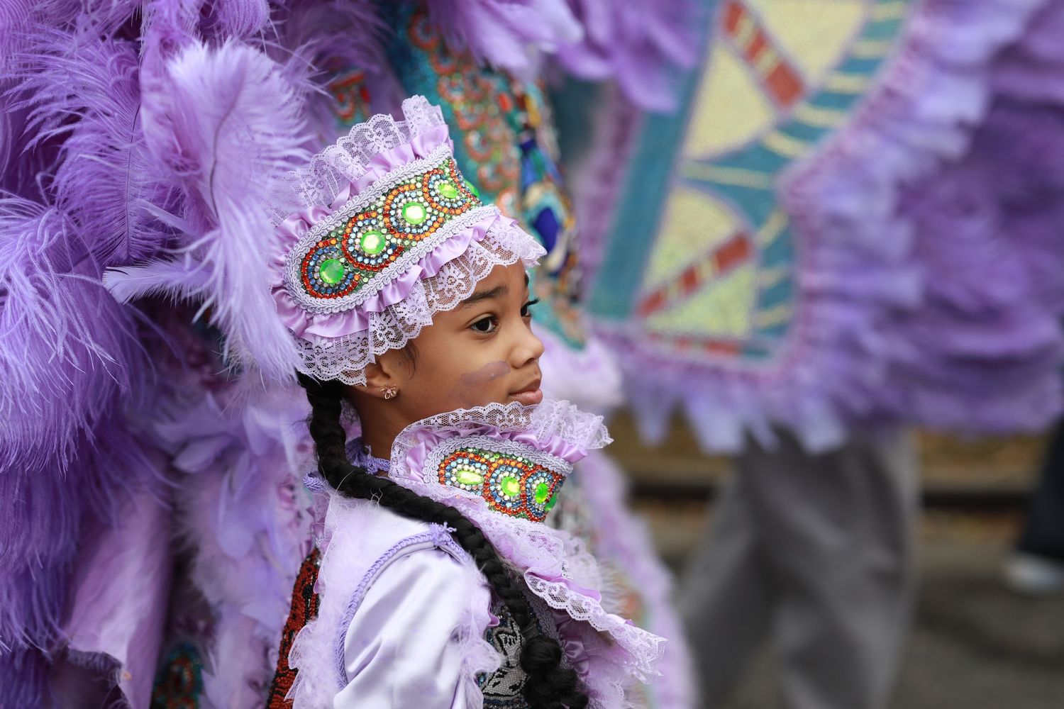 Mardi Gras performer wearing elaborate purple feathered costume and headdress during celebration.