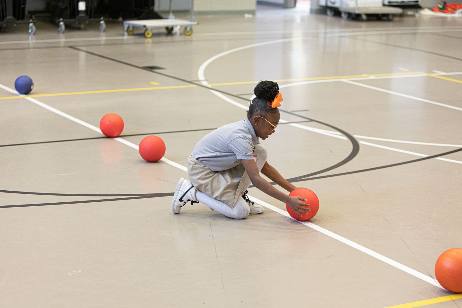 Student practicing basketball skills in a school gymnasium.