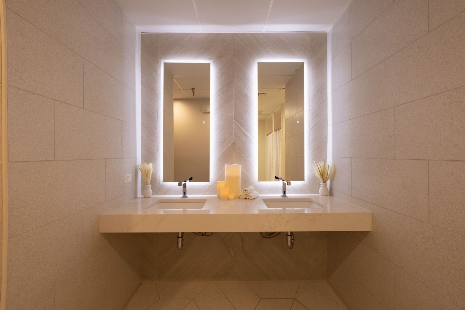 Modern bathroom vanity with illuminated double mirrors and white countertop.