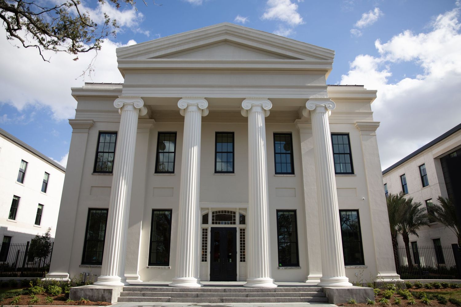 Classical white building facade with grand Corinthian columns and triangular pediment.