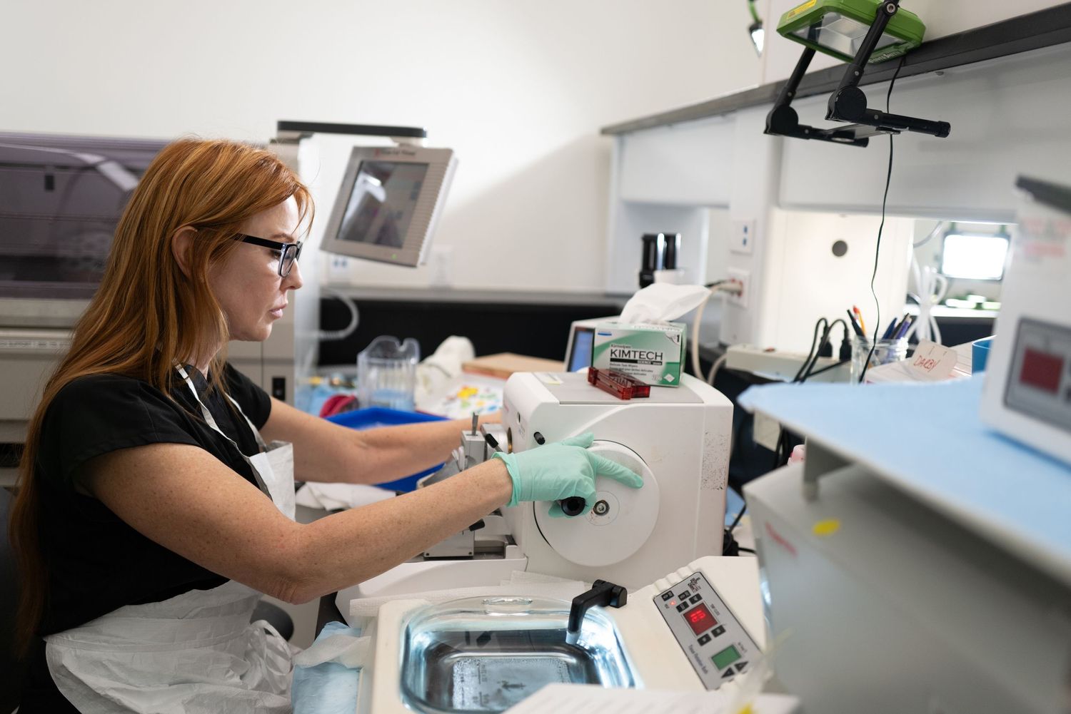 Laboratory technician operating medical analysis equipment in clinical testing facility.