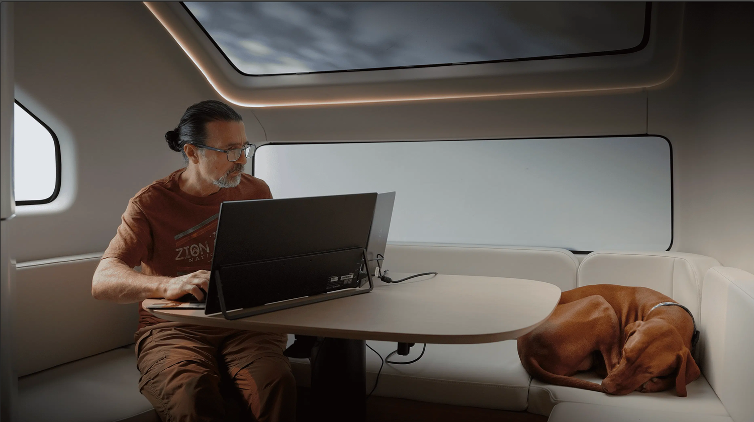 Man working on laptop in modern futuristic pod interior with curved walls and oval window.
