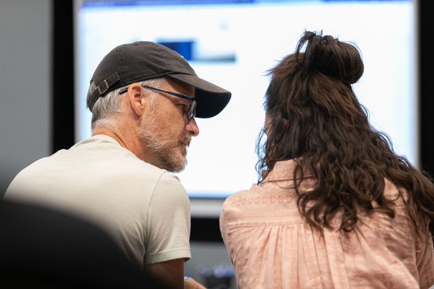 Two people sit together looking at a computer screen during a collaborative work session.