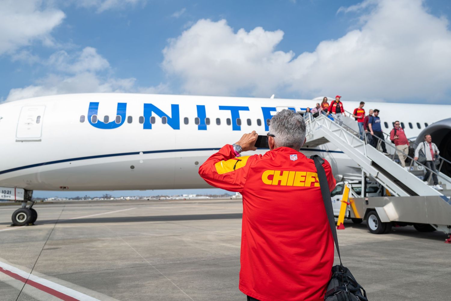 People boarding a United Airlines plane while wearing Chiefs gear.
