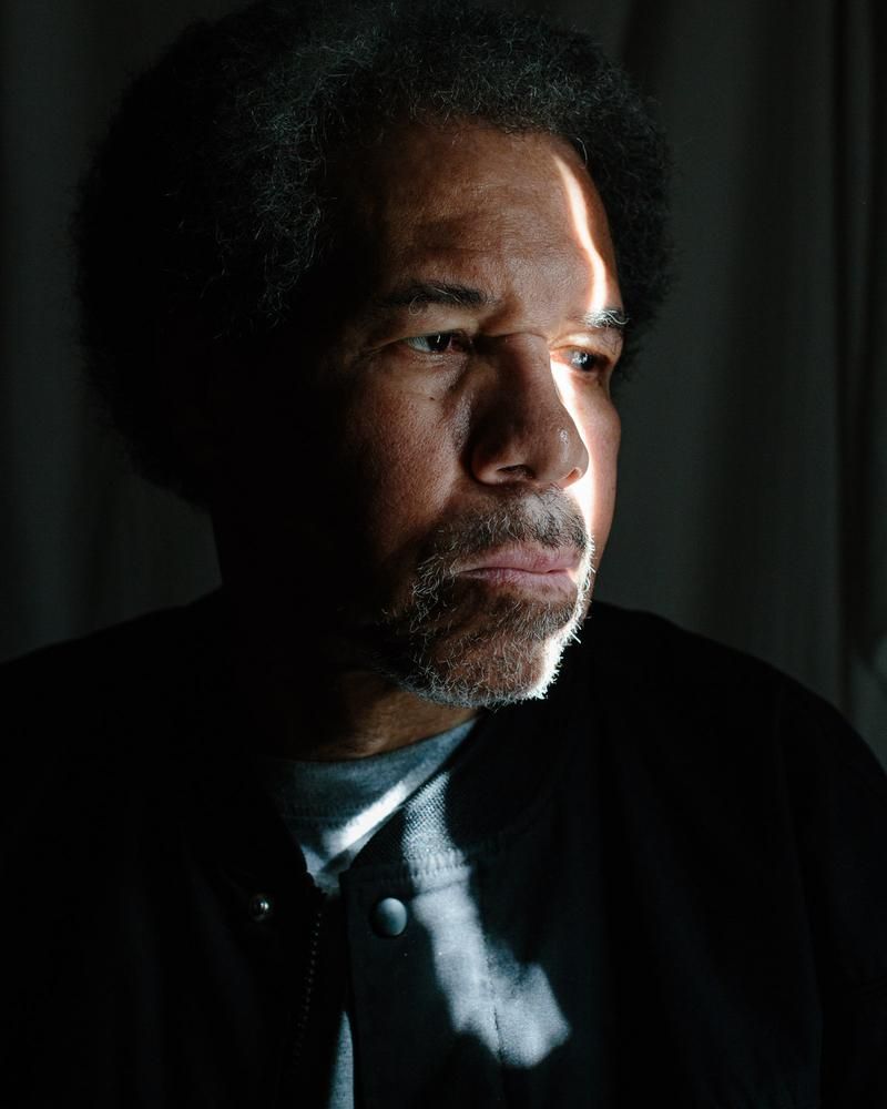 A series of moody portraits in dramatic lighting shows a figure in a suit emerging from shadows.