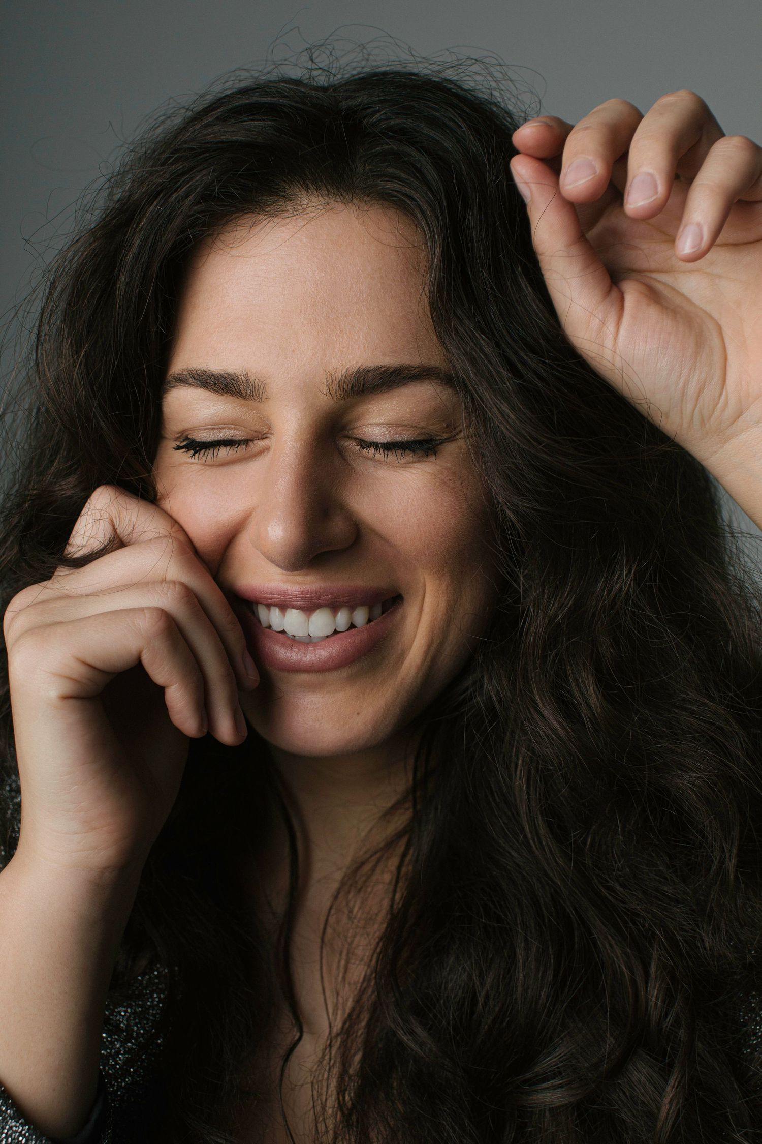 Close-up portrait of a joyful expression with dark flowing hair.