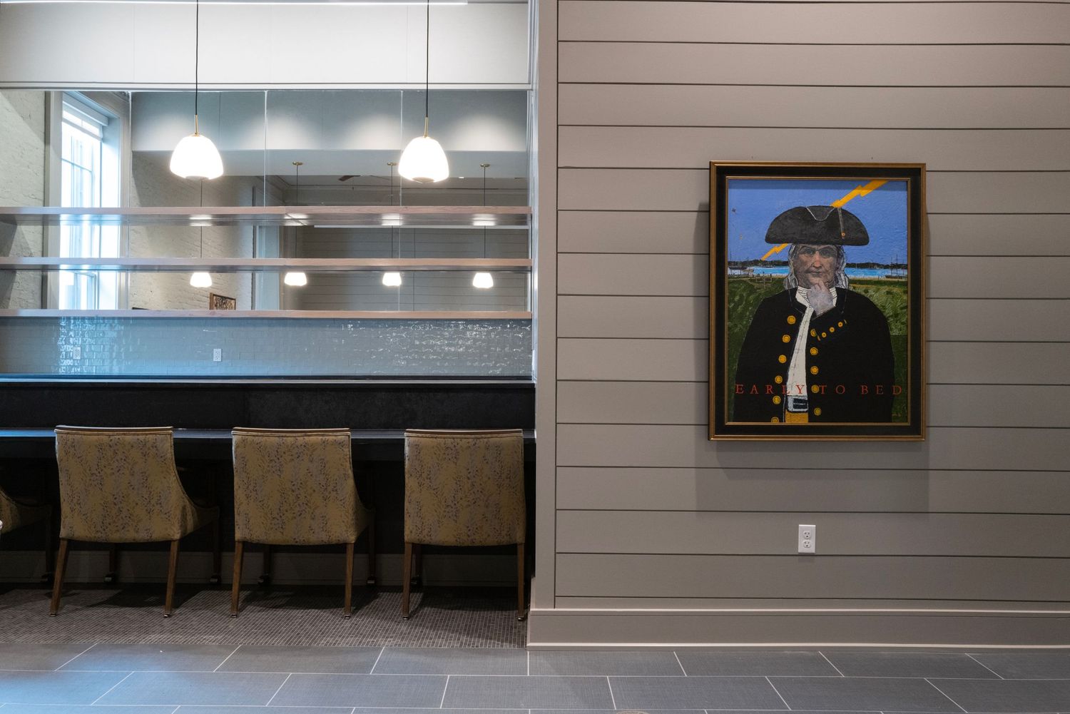 Restaurant interior with grey walls featuring whimsical artwork and modern bar seating.