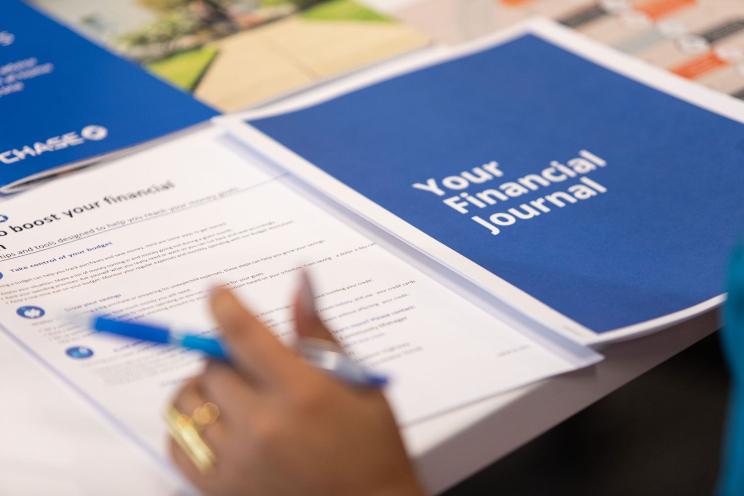 A close-up shot of hands reviewing financial documentation with a blue journal visible.