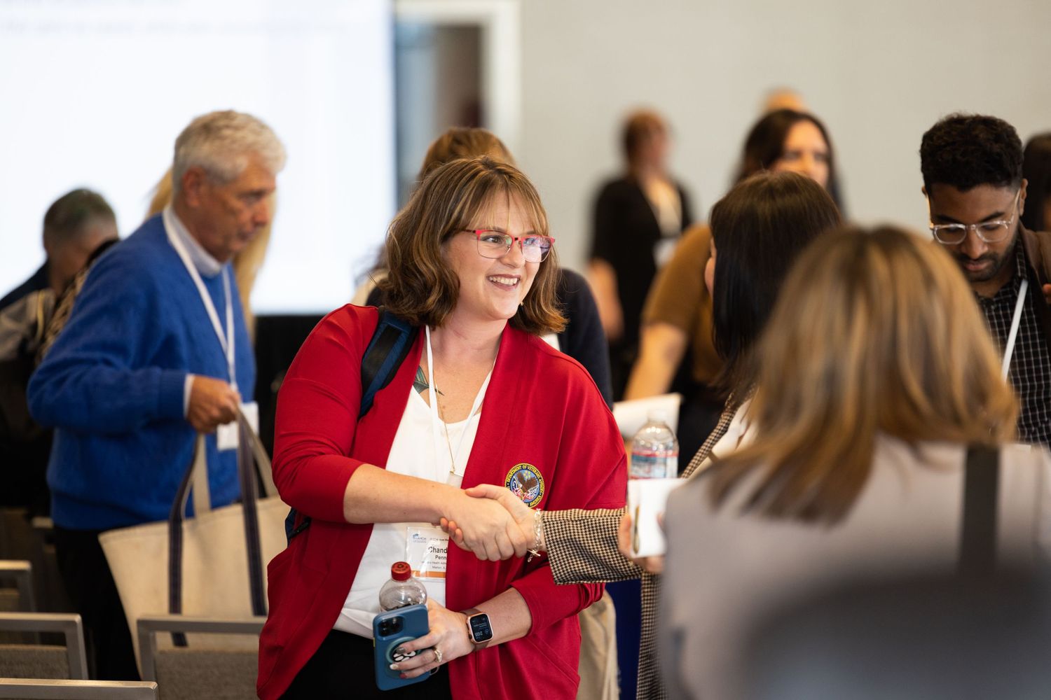 Conference attendee in red blazer networking at professional event.