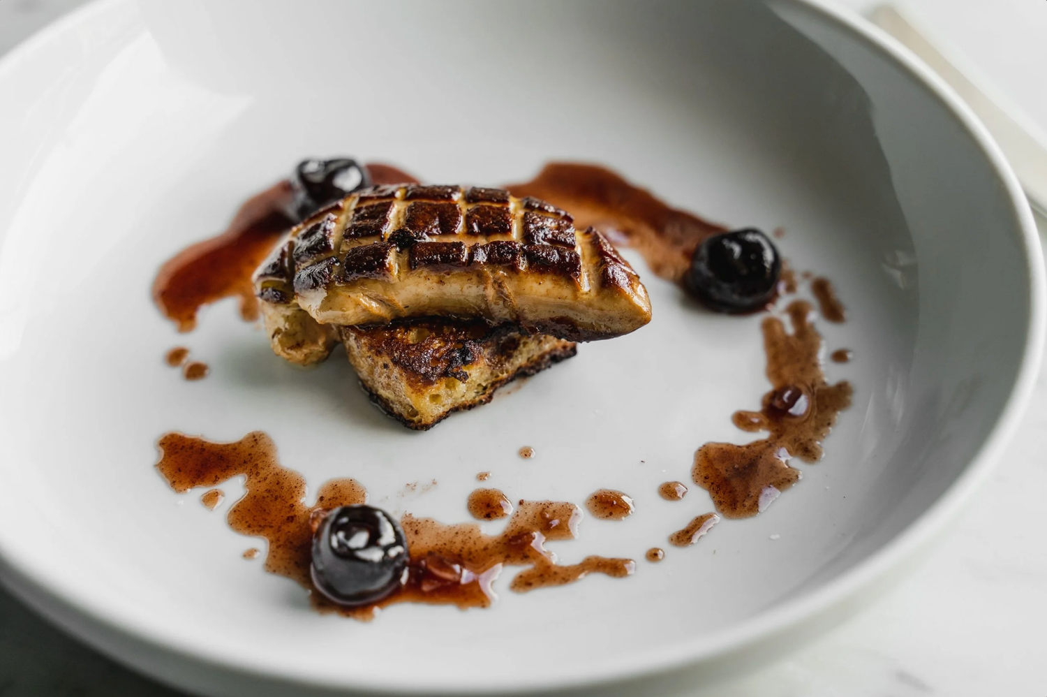 Plated dish showing remnants of food and dark sauce on a white ceramic plate.