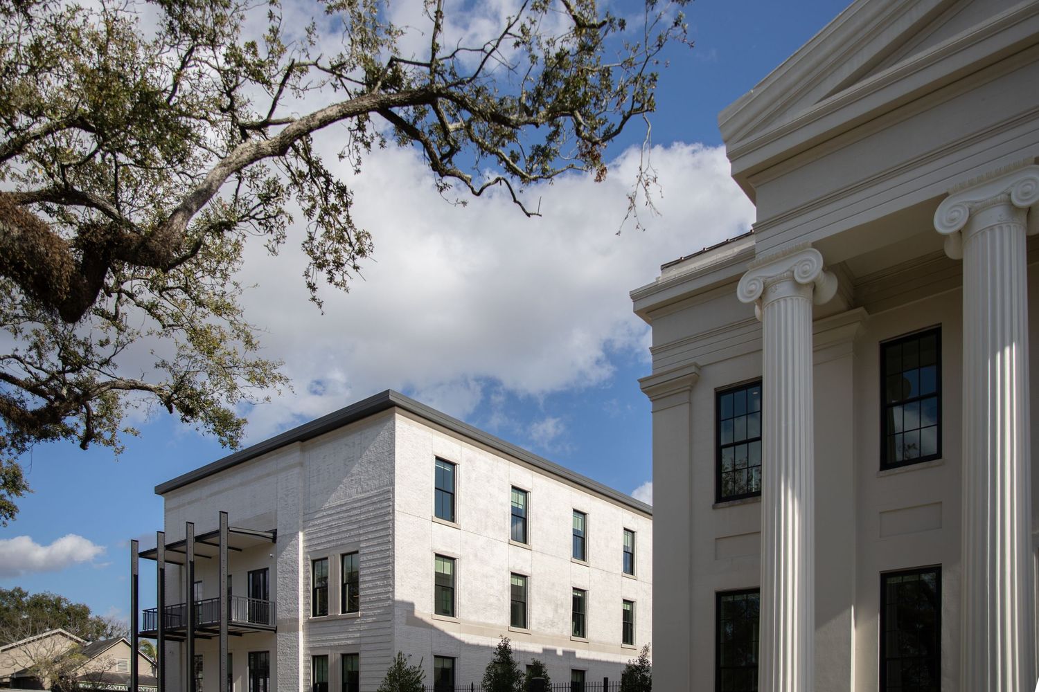 Historic white colonial buildings with classic columns and architectural details under cloudy sky.