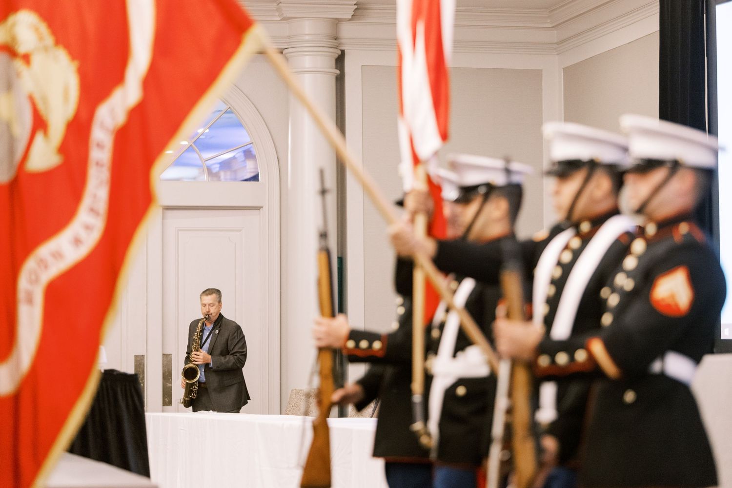 Honor guard members display flags during an official ceremony in an elegant room.