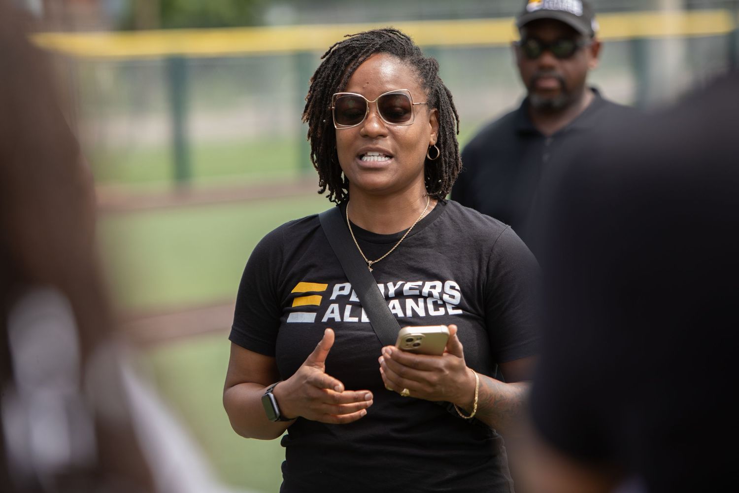 Instructor in Players Alliance t-shirt leading outdoor baseball training session.
