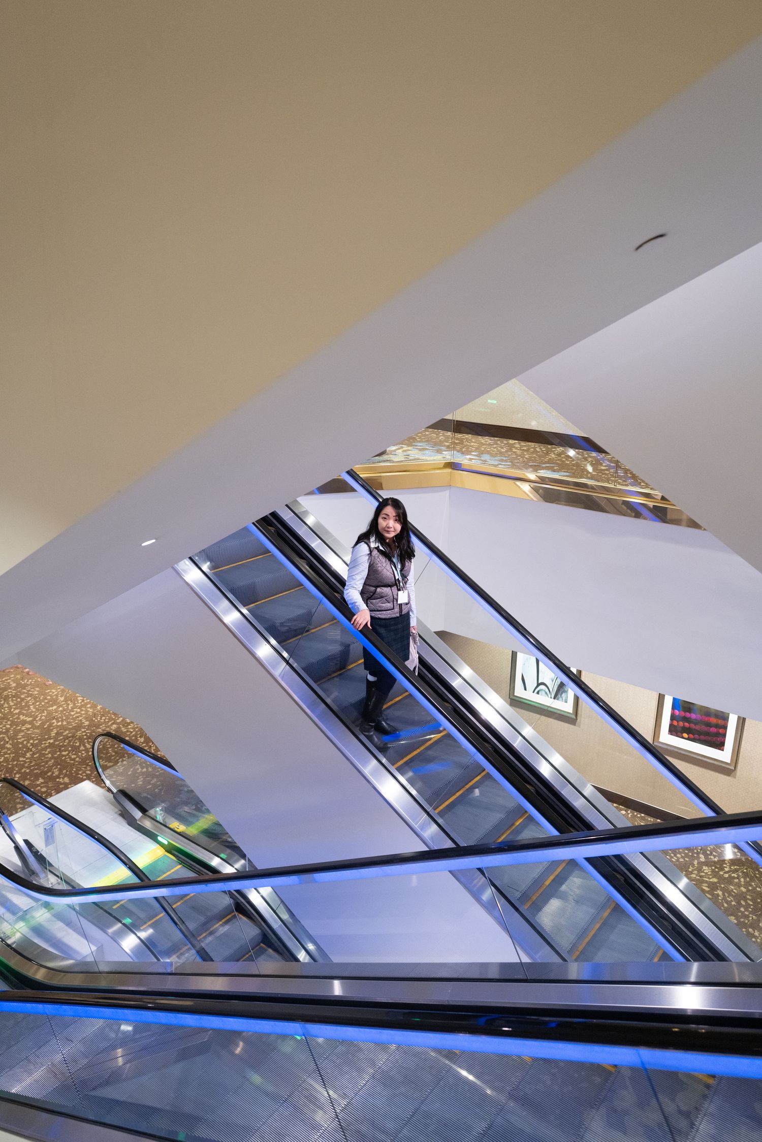 Person riding down escalator in modern building interior.