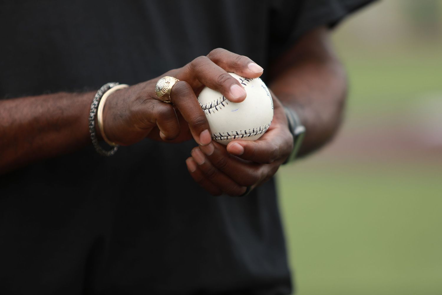 Close-up shot of hands gripping a baseball on an outdoor field.