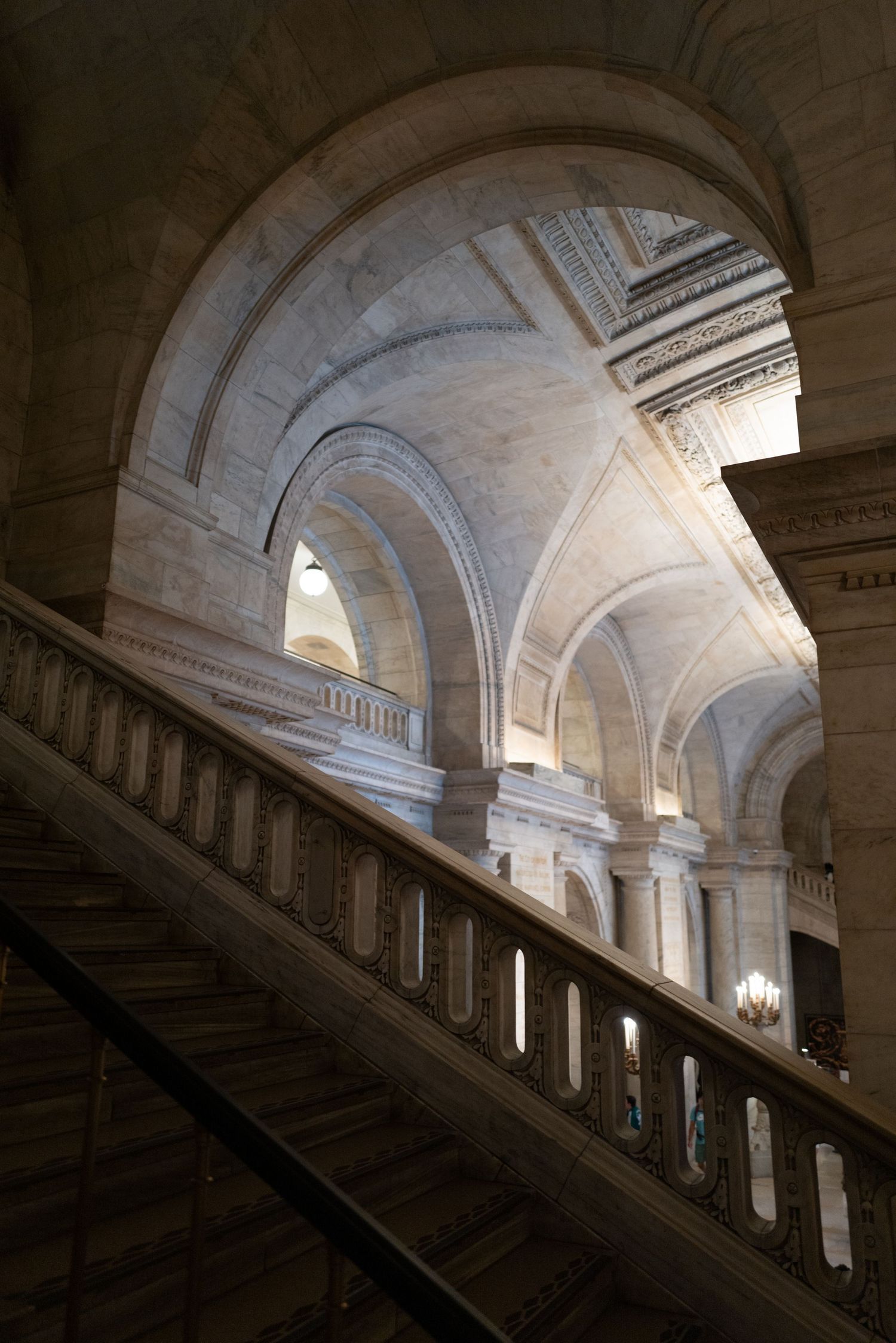 Grand marble staircase with ornate arched ceilings inside a historic neoclassical building interior.