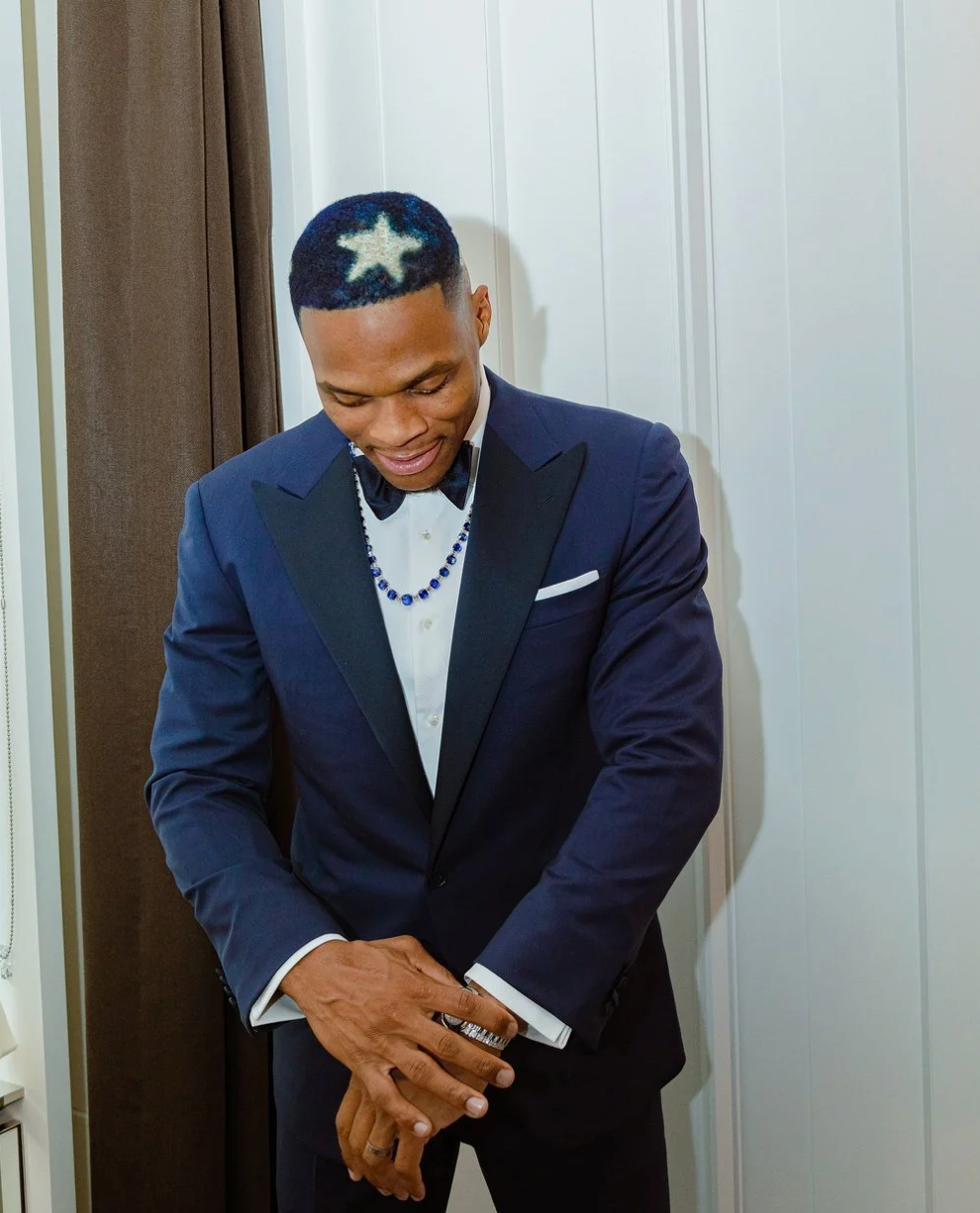 Athletes in navy blue suits bow their heads in prayer before a sporting event.