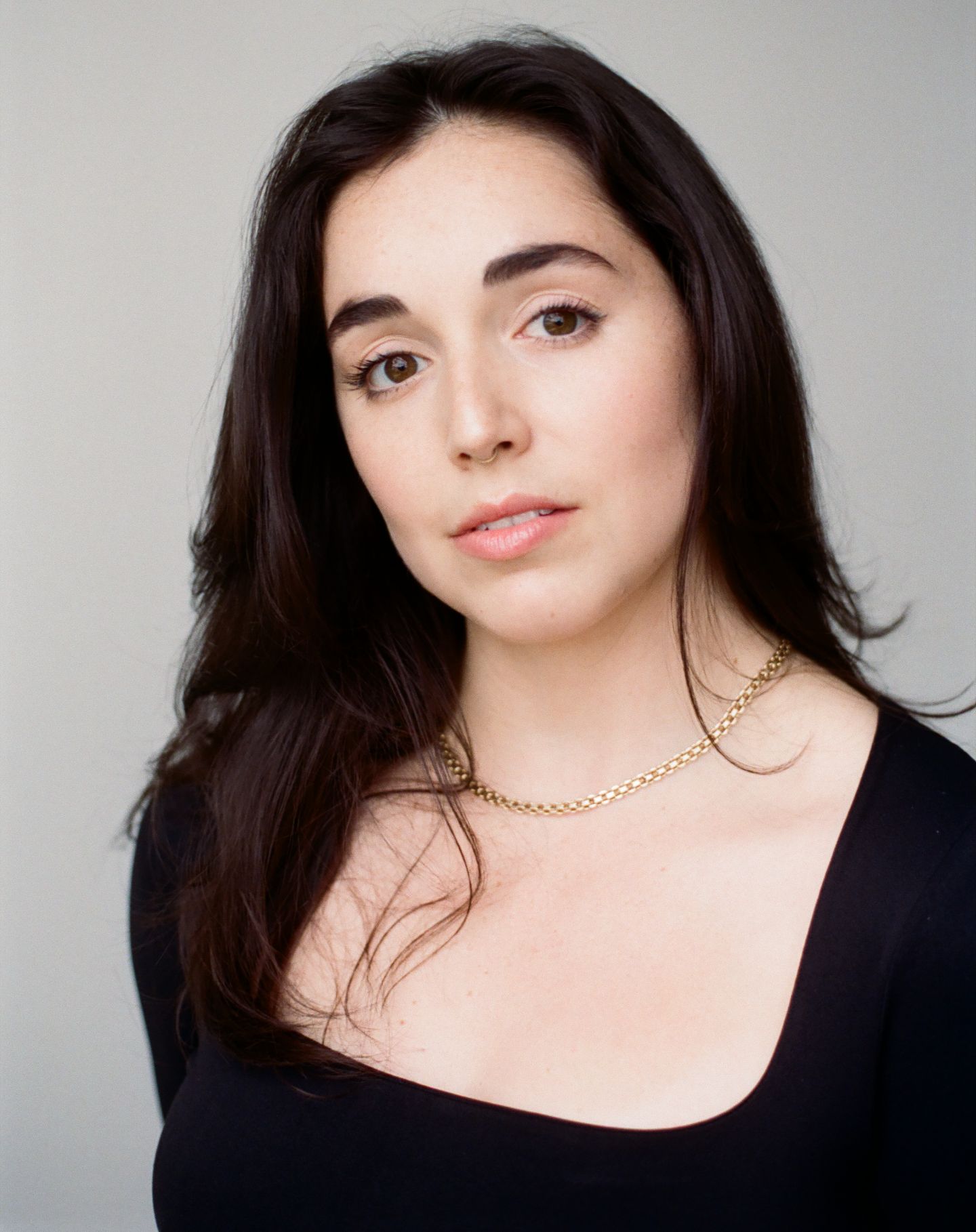 Studio portrait series showing elegant poses against a gray background wearing a black top and gold necklace.