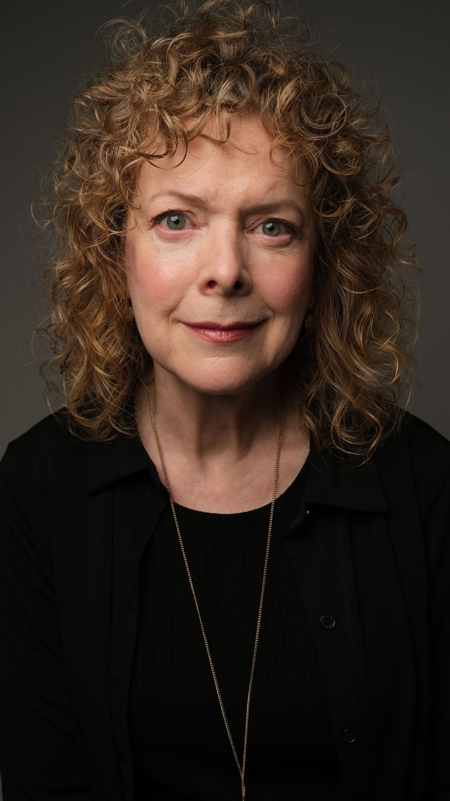 Studio portrait series showing bright expressions against dark background wearing black top and delicate necklace.