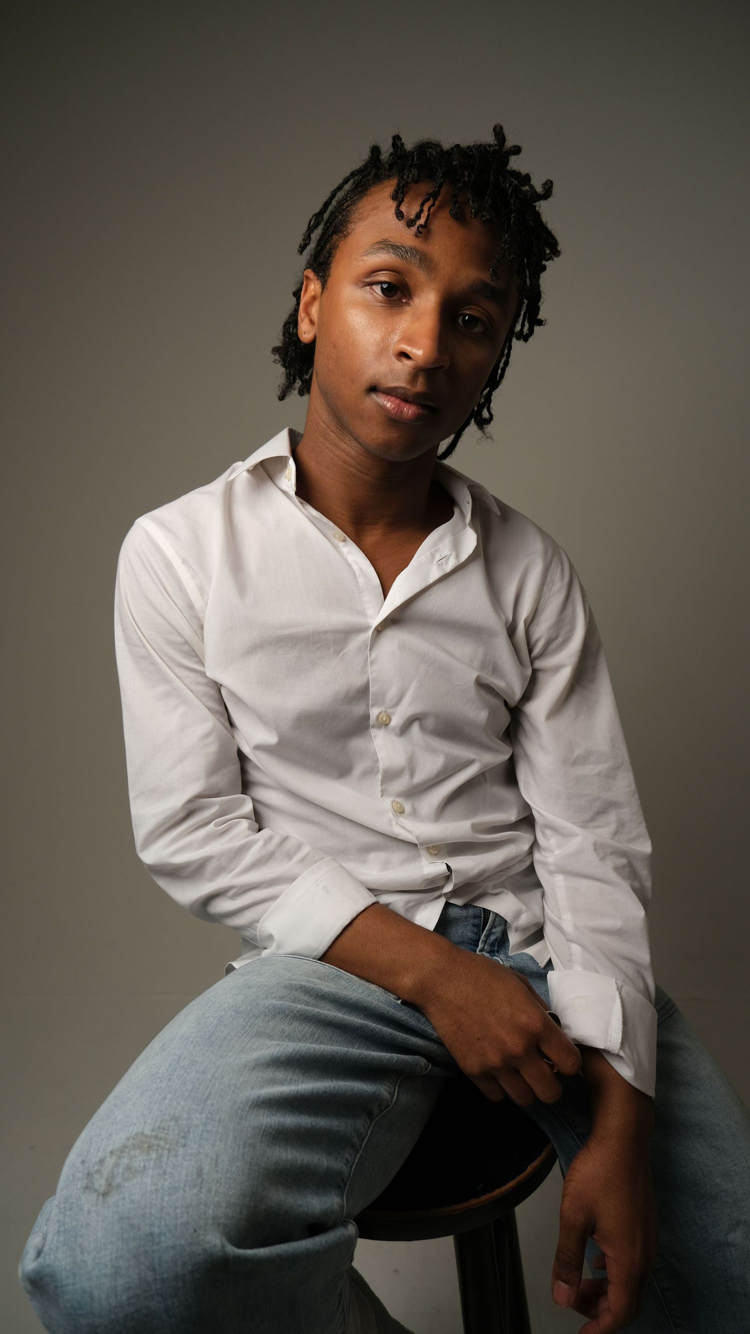 A series of artistic portraits of a young person in denim and white shirt against a minimalist gray background.