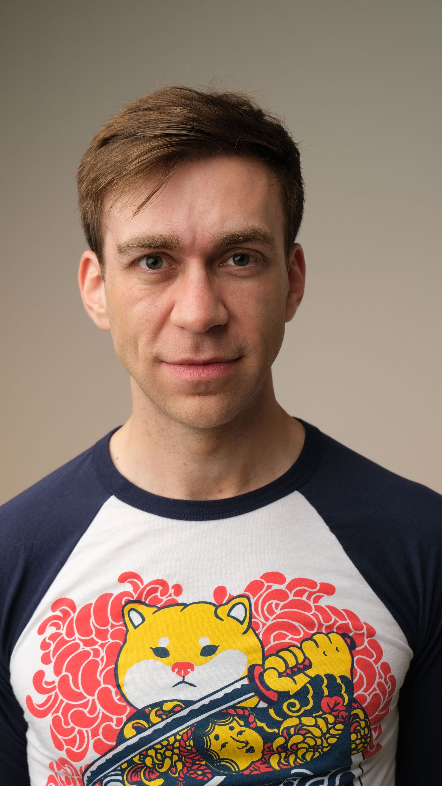 Person wearing a navy and white baseball t-shirt with colorful cat artwork featuring pink clouds and yellow details.