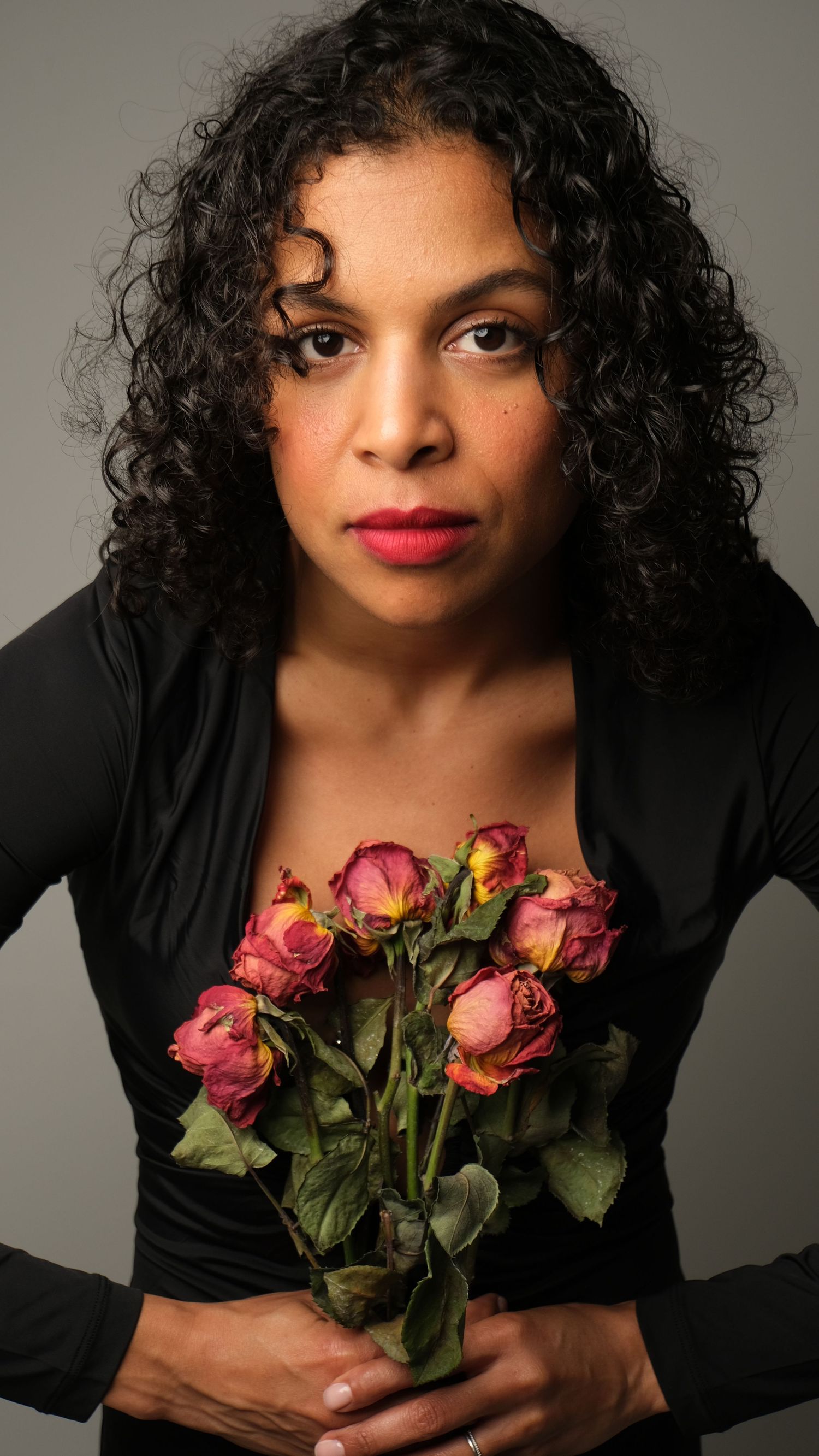 A portrait series shows someone in a black top holding pink roses against a gray backdrop.