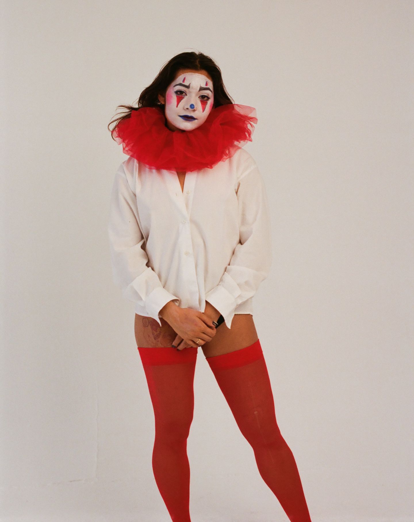 A performer in white shirt and red tights poses dramatically against a light background in multiple dance-like positions.