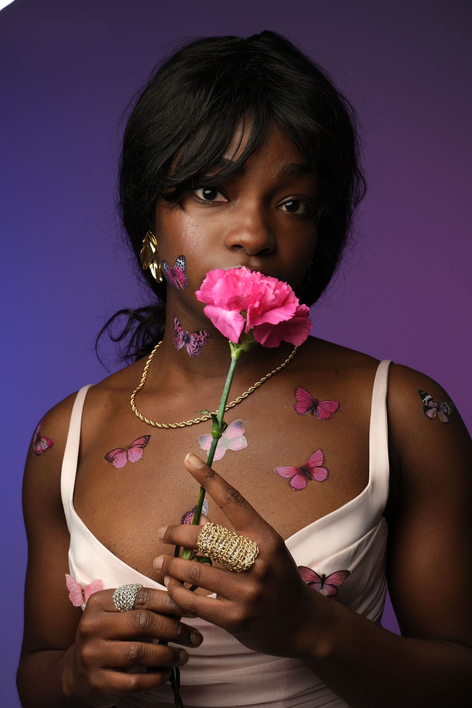 A series of artistic fashion portraits featuring pink roses and butterflies against a purple backdrop with gold jewelry details.